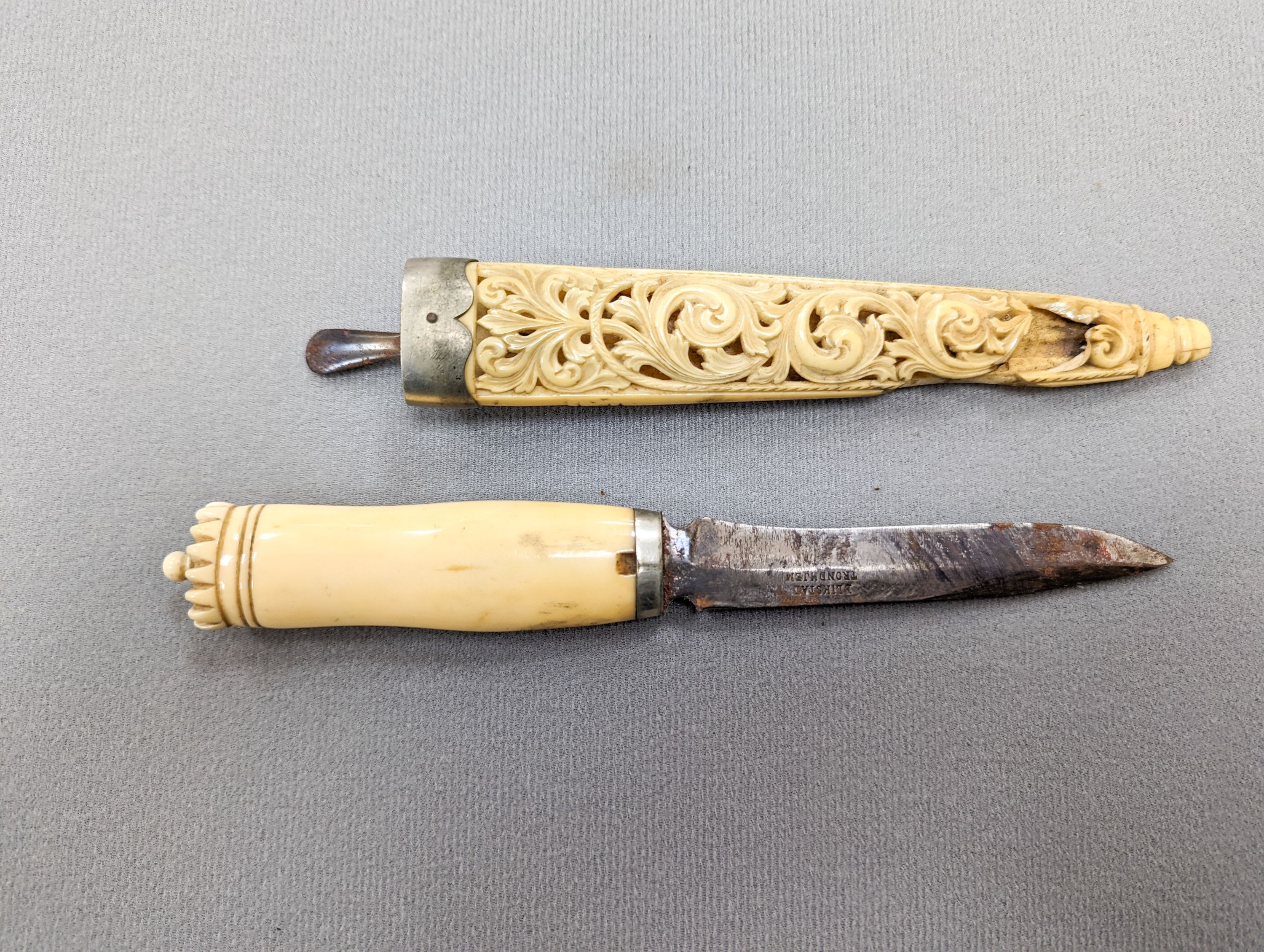 An antique Norwegian marine ivory hunting knife, with carved and pierced scabbard and leather outer sheath, the blade signed Blikstad, Trondhjem, scabbard damaged, overall 26.5cm.
